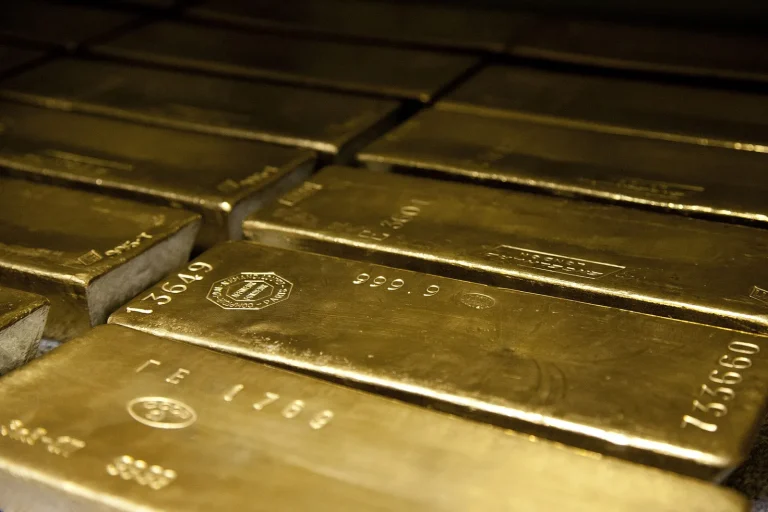 Gold’s Quiet Appeal in Noisy Times — and the Sceptics’ Questions Large cast gold bars stacked in rows
